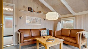 A cozy living room with a brown leather sectional sofa, a wooden coffee table, and a framed picture on the wall.
