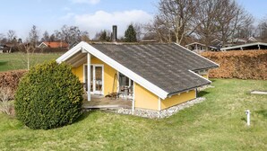 A yellow house with a sloped roof and a small porch.