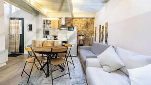 Eine moderne Küche mit einer Steinwand, einem Essbereich mit Holztisch und -stühlen sowie einem grauen Sofa.