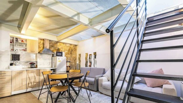 Eine moderne Küche mit Essbereich, einer Treppe und einem Wohnzimmer mit Sofa.