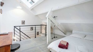 Ein Schlafzimmer mit Bett, Schreibtisch und einer Treppe zu einer oberen Ebene.