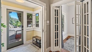 Un couloir avec une porte donnant sur un garage, un petit banc et un tapis sur le sol.