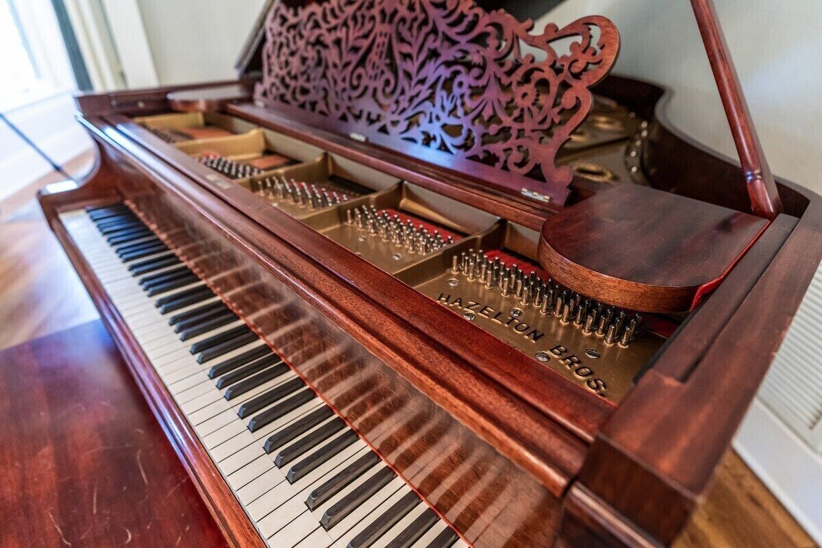 Un piano de cola de madera con un atril decorativo.