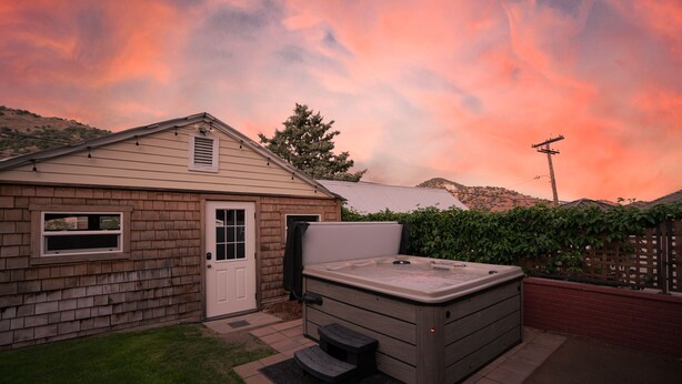A house with a hot tub in the backyard, a garage, and a wooden fence.