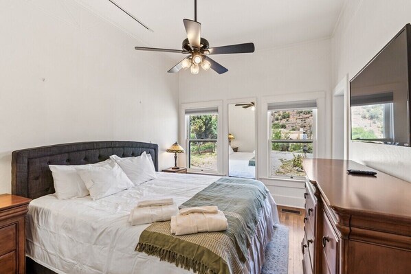 A bedroom with a bed, bedside tables, a ceiling fan, and a TV.