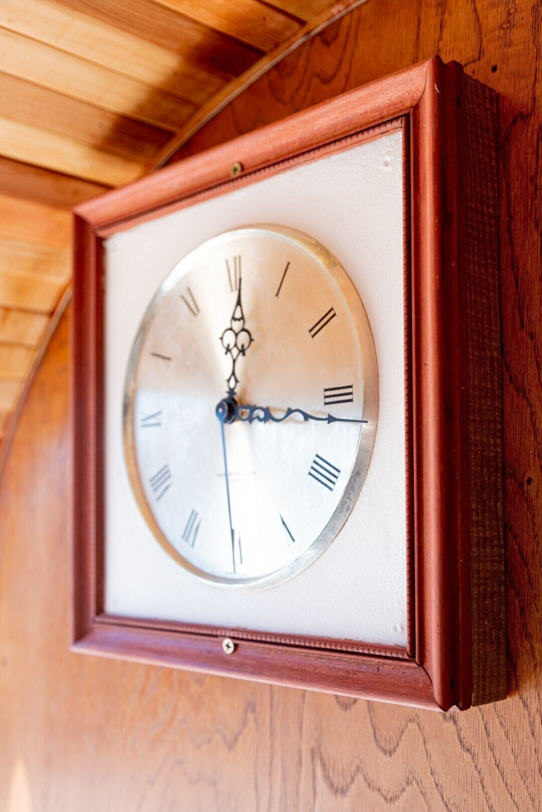 Une horloge murale avec un cadre en bois et un cadran blanc.