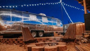 A stationary trailer with a fire pit and two wooden chairs in front. - NEW! Cozy, Desert Dream Airstream with Firepit (Tombstone)