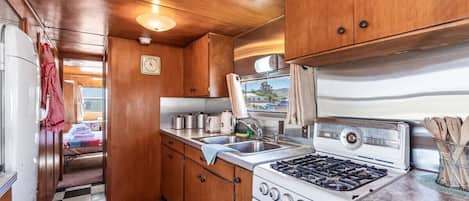 A compact kitchen with wooden cabinets, a stove, and a sink.