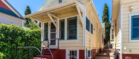 A two-story house with a front porch, a staircase leading to the entrance, and a small front yard.
