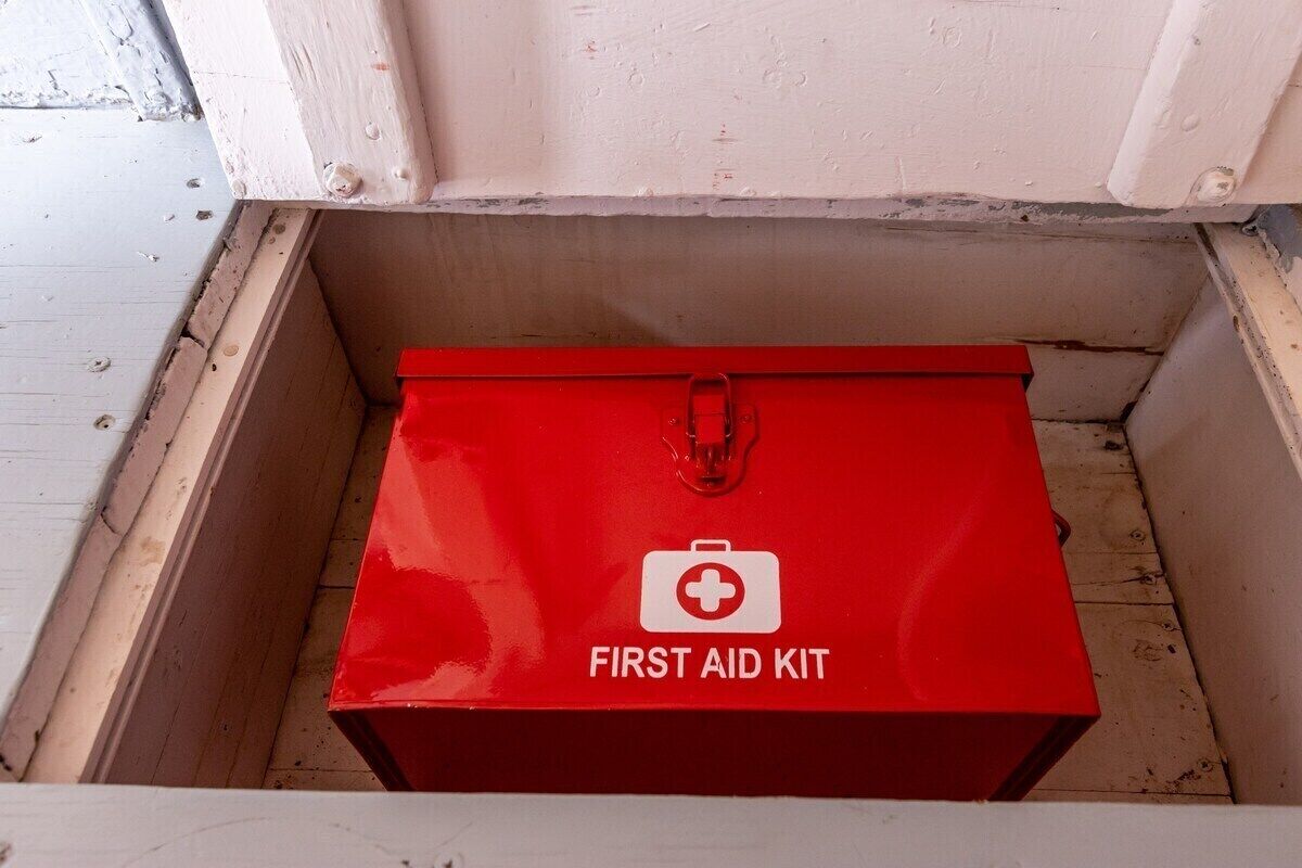 A red first aid kit in a wooden drawer.