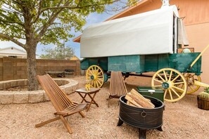 A covered outdoor seating area with wooden chairs and a fire pit.
