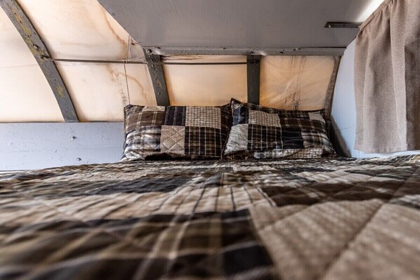 A bunk bed with a quilted bedspread and two pillows.