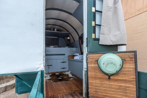 A compact kitchen with a wooden counter, a hanging pot rack, and a small sink area.