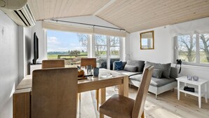 A cozy room with a wooden ceiling, a dining table with chairs, a sofa, and a TV. - 1 bedroom awesome apartment in Grevinge (Grevinge)