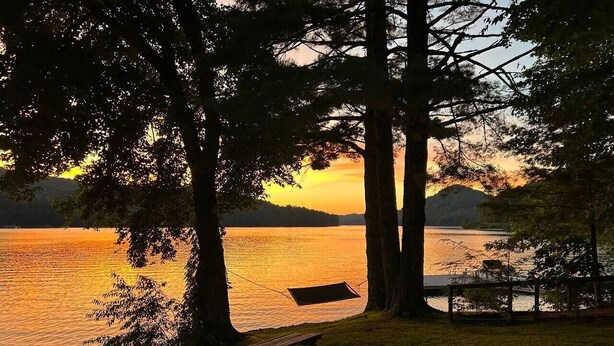 Eine Bank und ein Picknicktisch am See bei Sonnenuntergang.