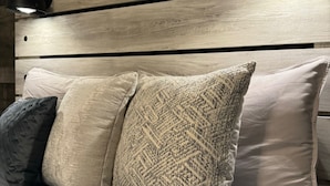 A bed with a wooden headboard and three pillows in different patterns. - Beautiful Waukesha Home (Waukesha)