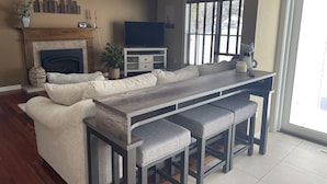 A modern living room with a built-in kitchen island, a fireplace, and a large window. - Beautiful Waukesha Home (Waukesha)