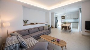 Ein modernes Wohnzimmer mit einer Couch, einem Couchtisch und einem Essbereich mit Tisch und Stühlen.