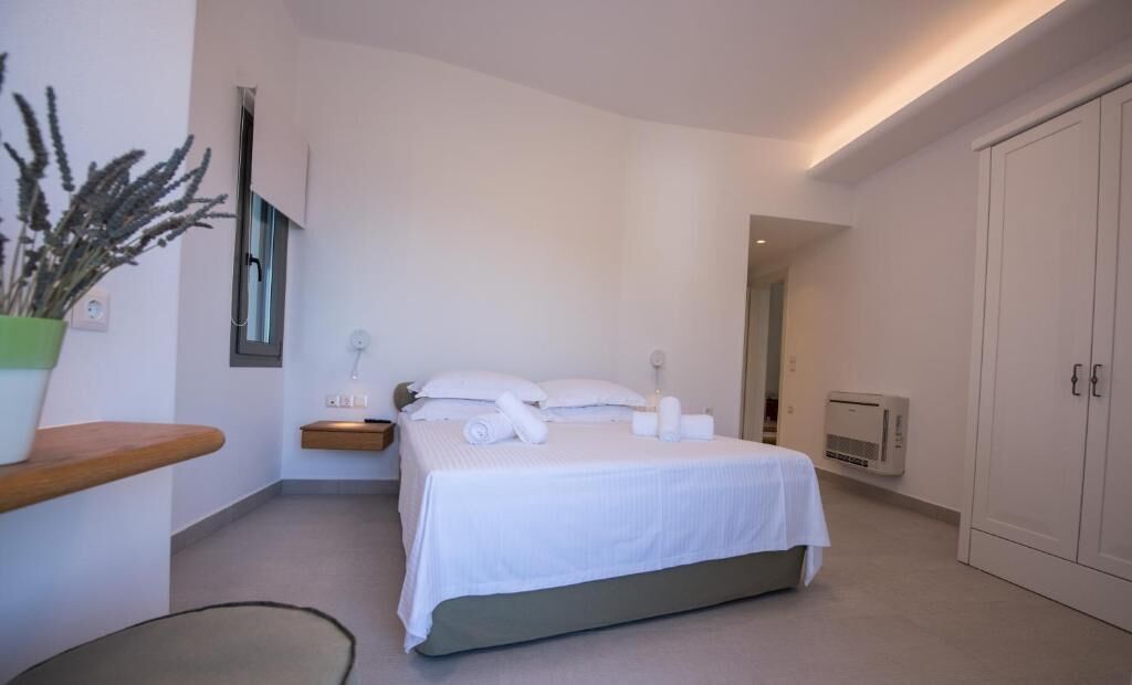 A modern bedroom with a bed, bedside table, and a potted plant.