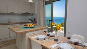 Eine moderne Küche mit Holzausziehtisch, weißen Schränken und einer Essecke mit Tisch für zwei Personen.