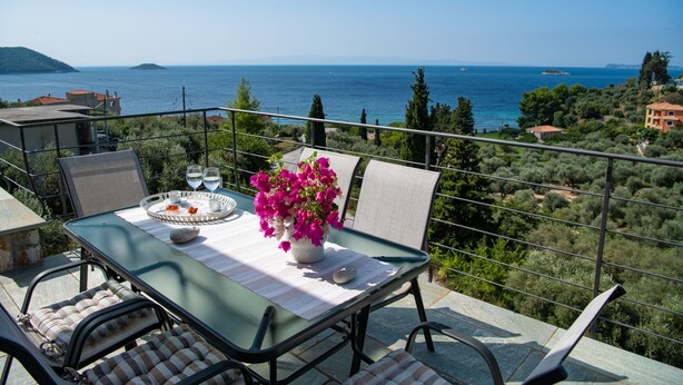 Ein Balkon mit Tisch für zwei Personen, mit Blick auf eine Küstenlandschaft.