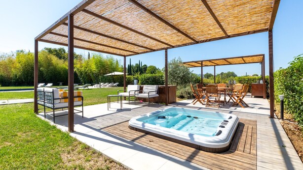A covered outdoor area with a hot tub, lounge chairs, and a wooden table. - Cozy home in Spoleto with WiFi (Spoleto)