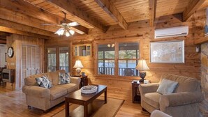 A cozy cabin interior with wooden walls and floors, a sofa set, a coffee table, and a fireplace.