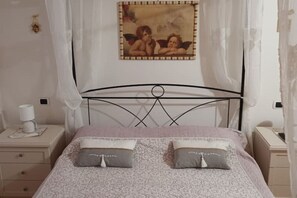 Cozy retreat with a bed, nightstand, and lamp, featuring a framed artwork above.