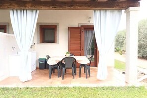Enjoy a dining experience under a covered pergola with a table and chairs.