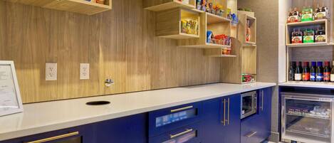 A modern kitchen with wooden shelves, a refrigerator, and a counter with drawers.