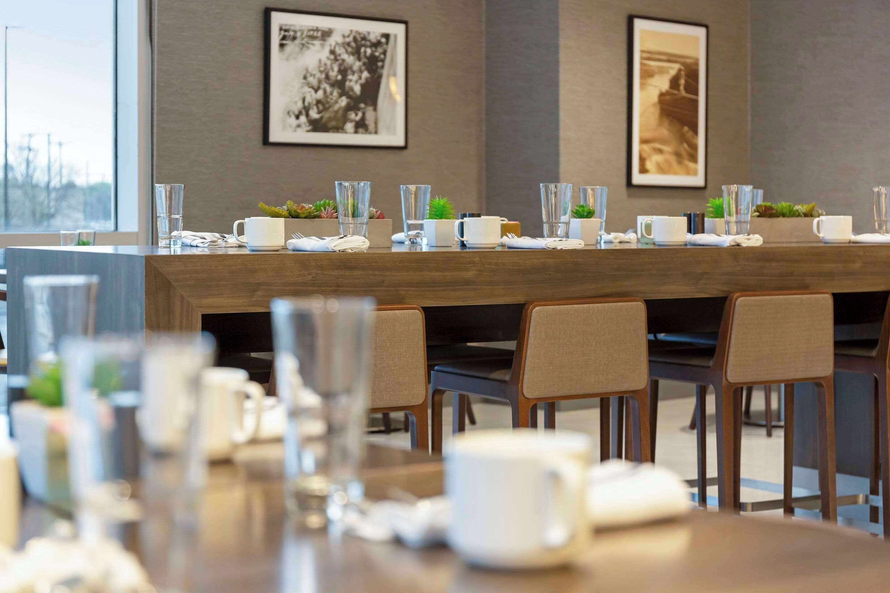 A conference room with a long table set for a meeting, chairs, and framed pictures on the wall.