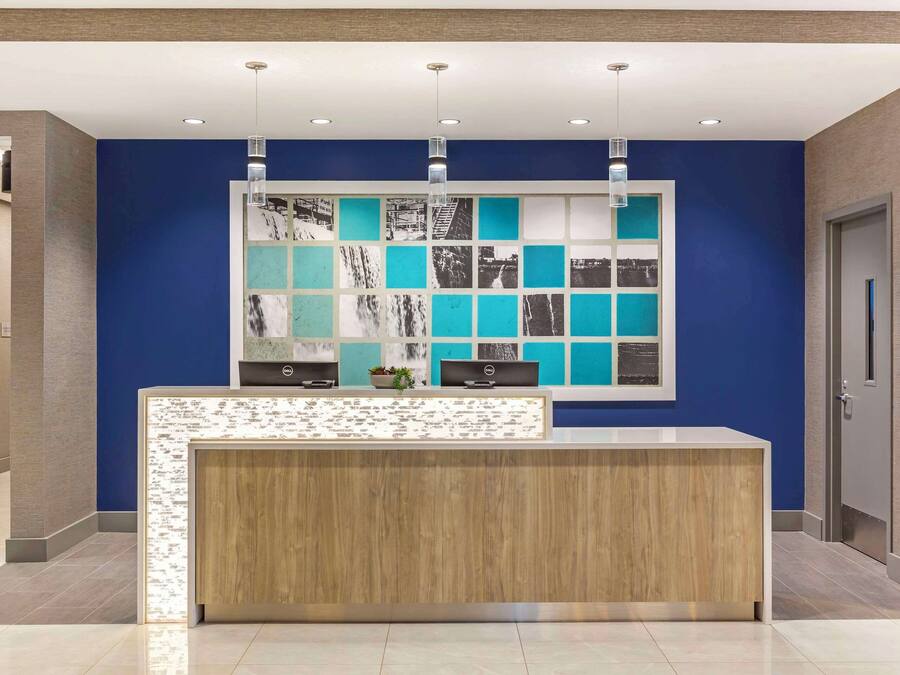 Un mostrador de recepción con pared azul y una obra de mosaico encima.