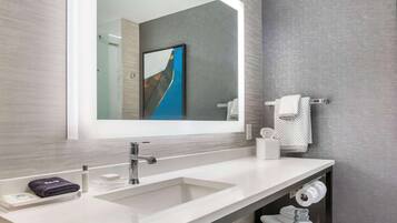 Un baño moderno con un espejo grande, lavamanos blanco y un perchero para toallas.