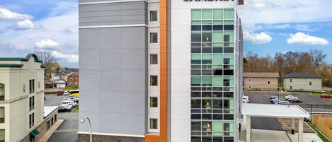 A modern building with a prominent 'CAMBRIA' sign, featuring a mix of glass and solid facade, and a parking area in front.