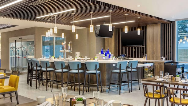 Un restaurant moderne doté d’un bar central, de plusieurs espaces de détente et d’un décor intérieur contemporain.