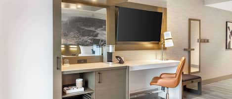 Una habitación de hotel moderna con escritorio, silla y un espejo grande.