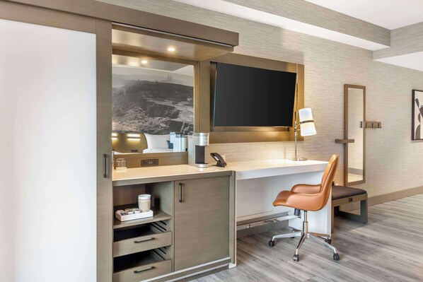 Una habitación de hotel moderna con escritorio, silla y un espejo grande.