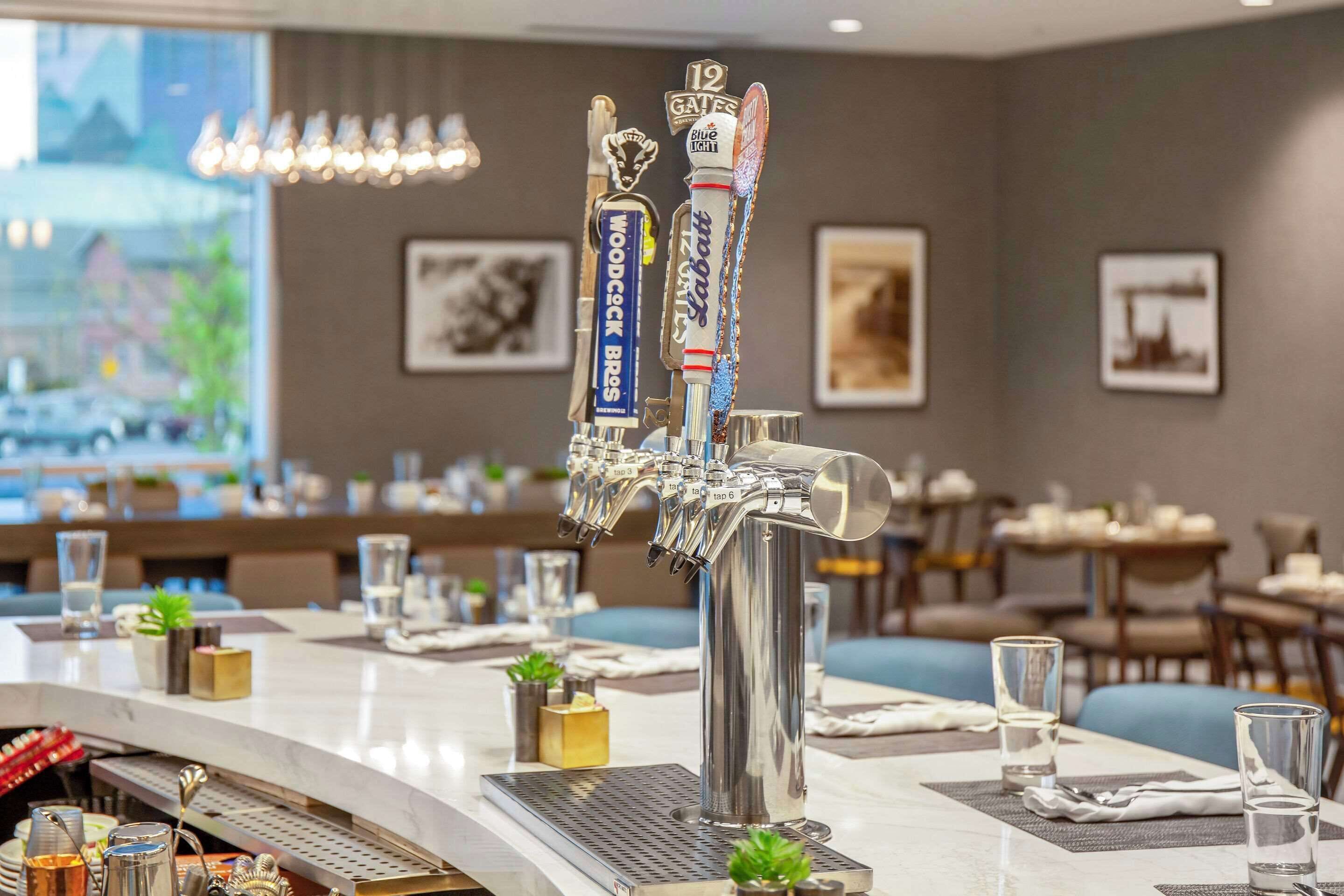 A bar area with multiple beer taps, glasses, and a bar counter.