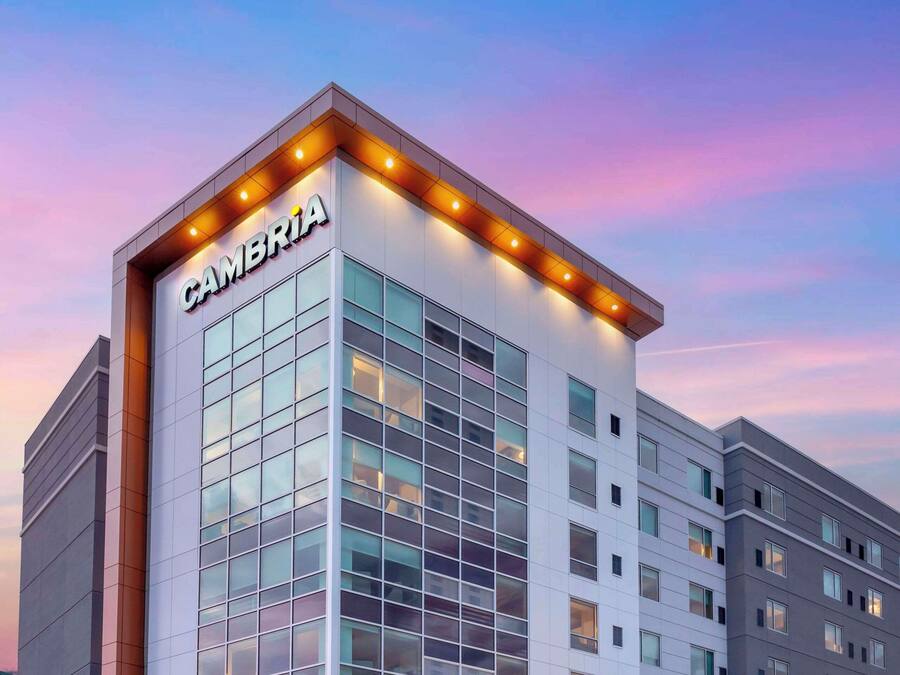 A modern hotel building with the name "CAMBRIA" prominently displayed on the facade.