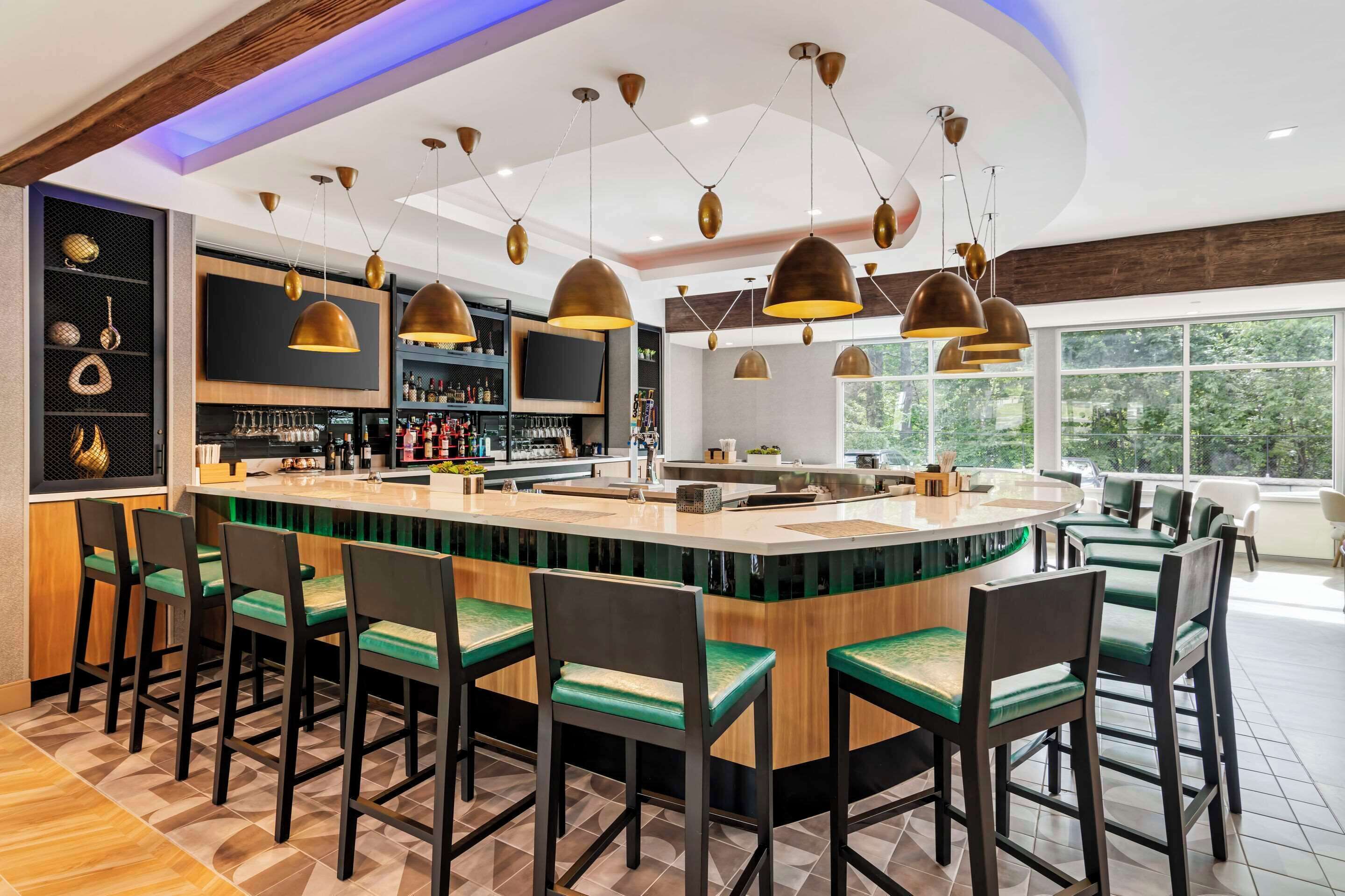 A modern bar area with a central island, bar stools, and pendant lighting.