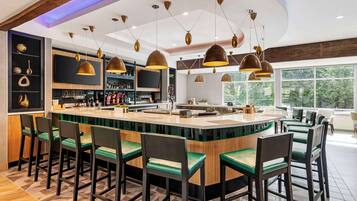 A modern bar area with a central island, bar stools, and pendant lighting.