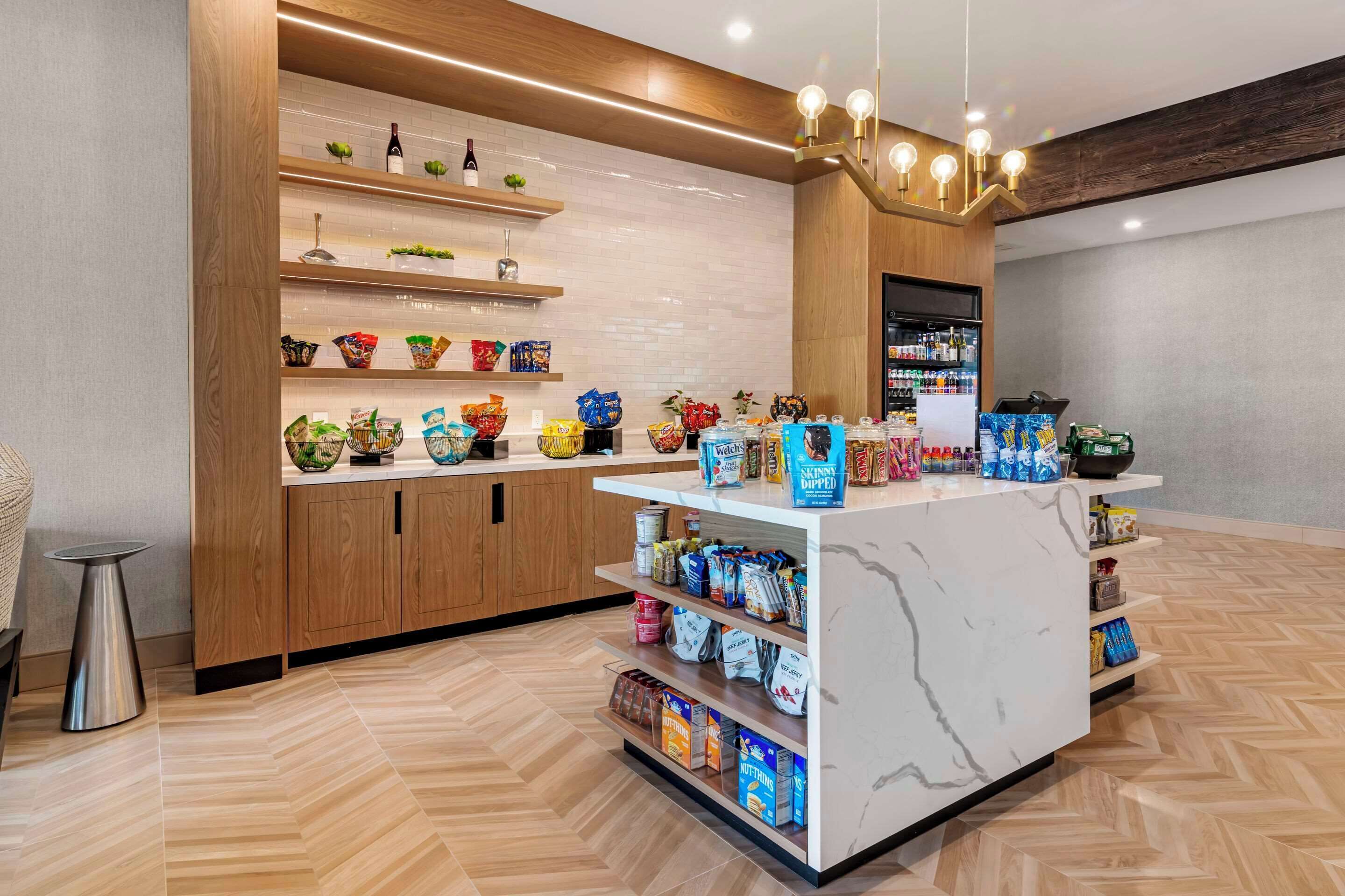 A modern retail area with wooden shelving, marble counter, and a variety of packaged goods.
