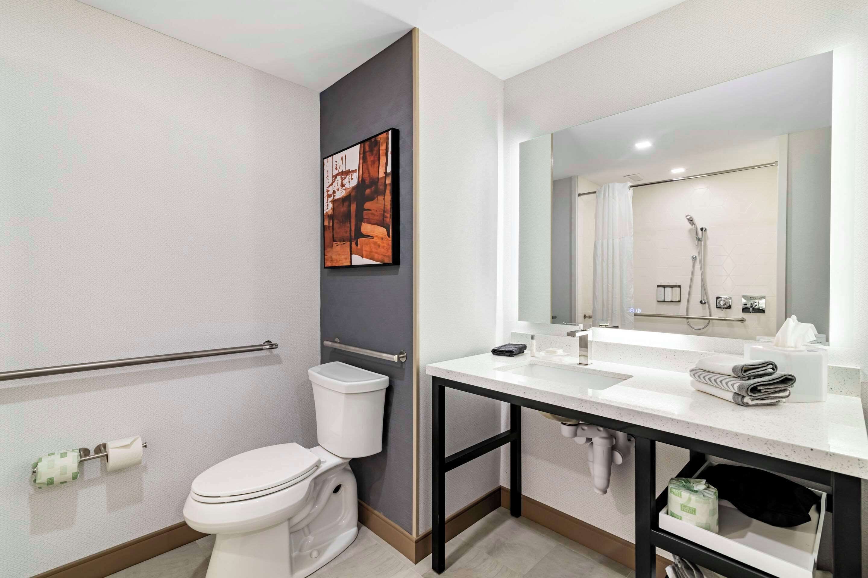 Un baño moderno con inodoro, lavamanos y ducha.