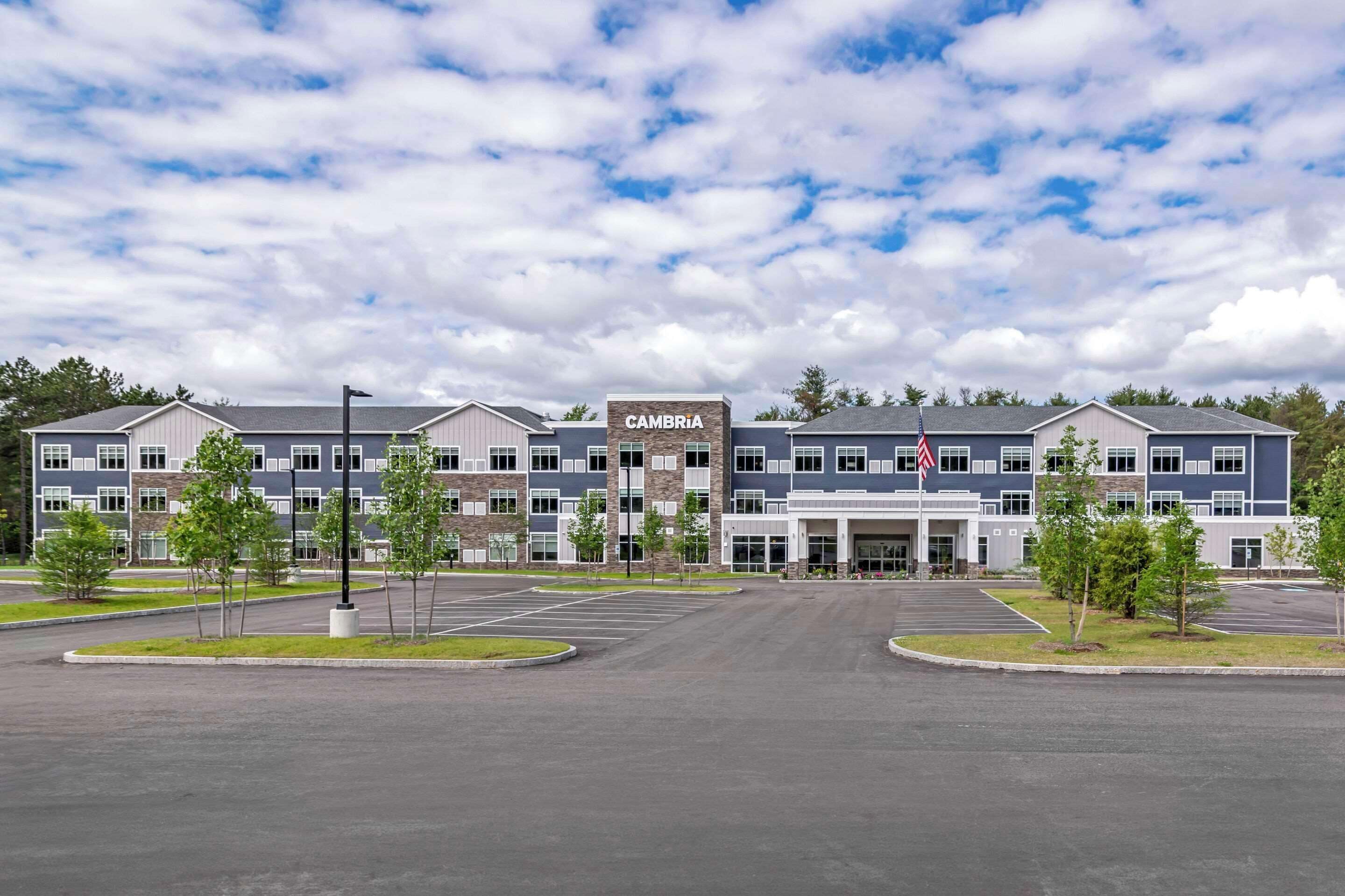 A modern building with a sign reading "CAMBRIA" and a parking lot in front.