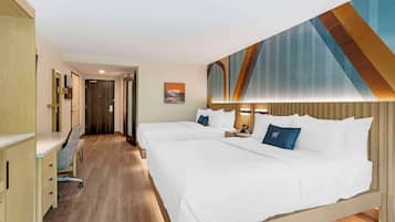 A hotel room with two beds, a desk, and a chair.
