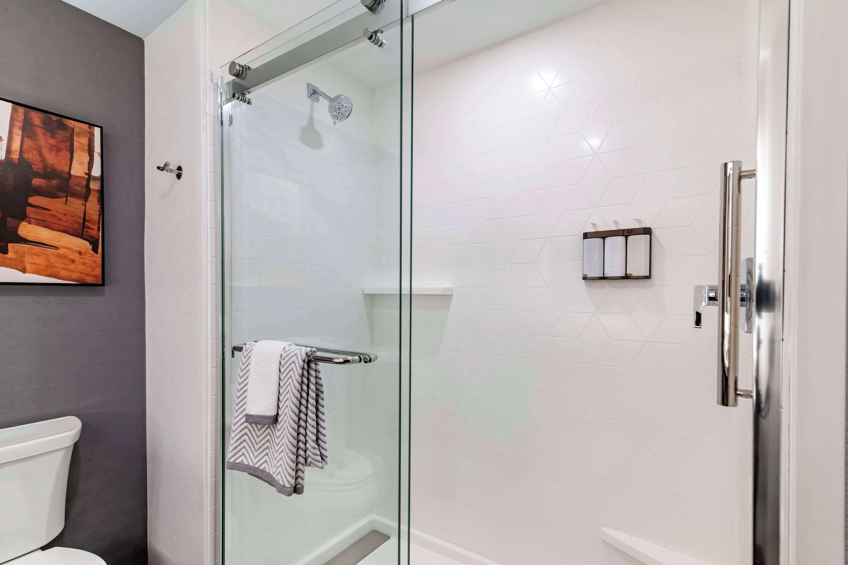 Ein modernes Badezimmer mit einer Glastrennwand-Dusche, einer Toilette und einem Handtuchhalter.