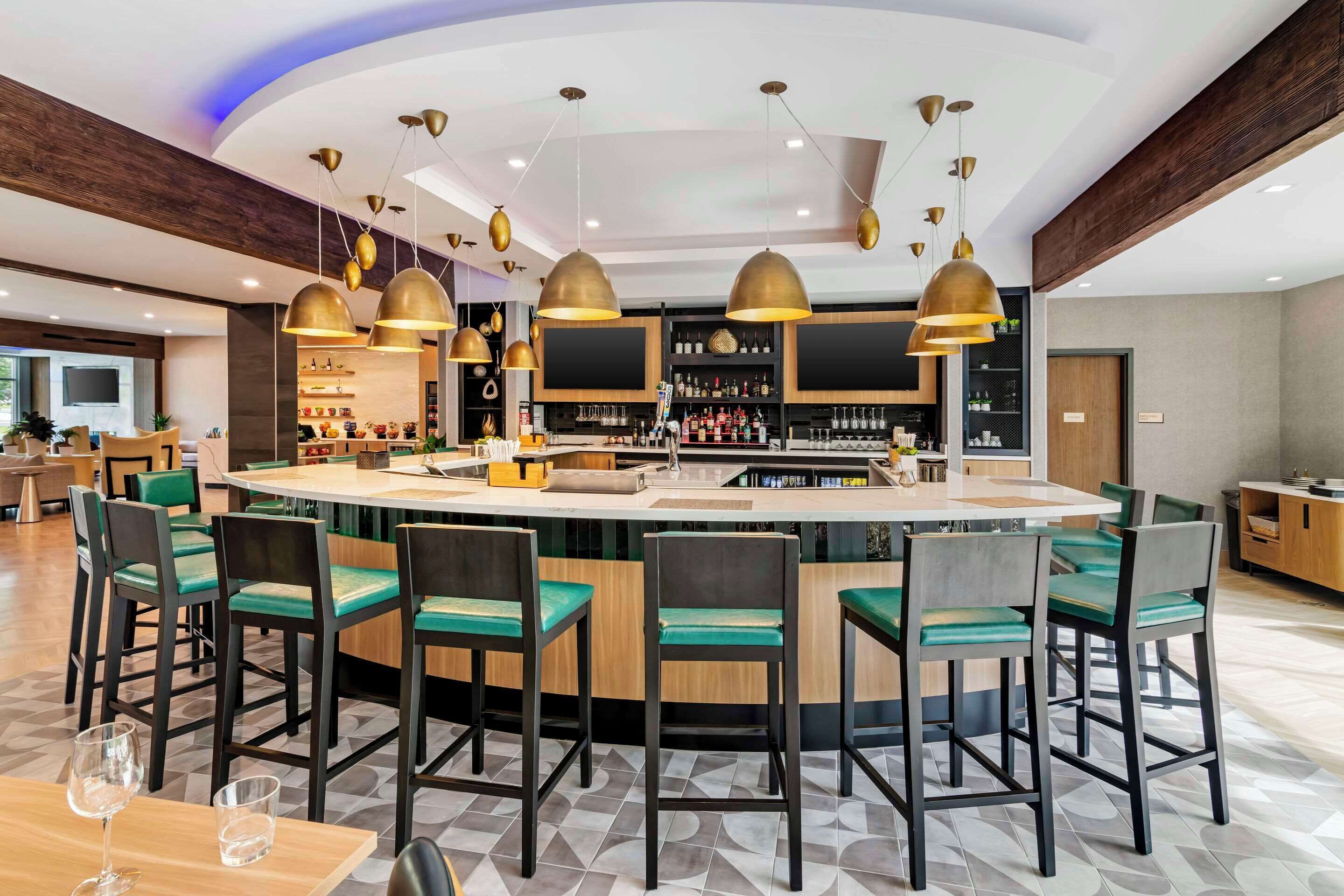 A modern bar area with a central island, bar stools, and pendant lighting.