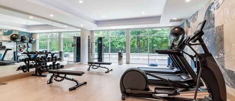 A modern gym with treadmills, weight machines, and a mirror wall.
