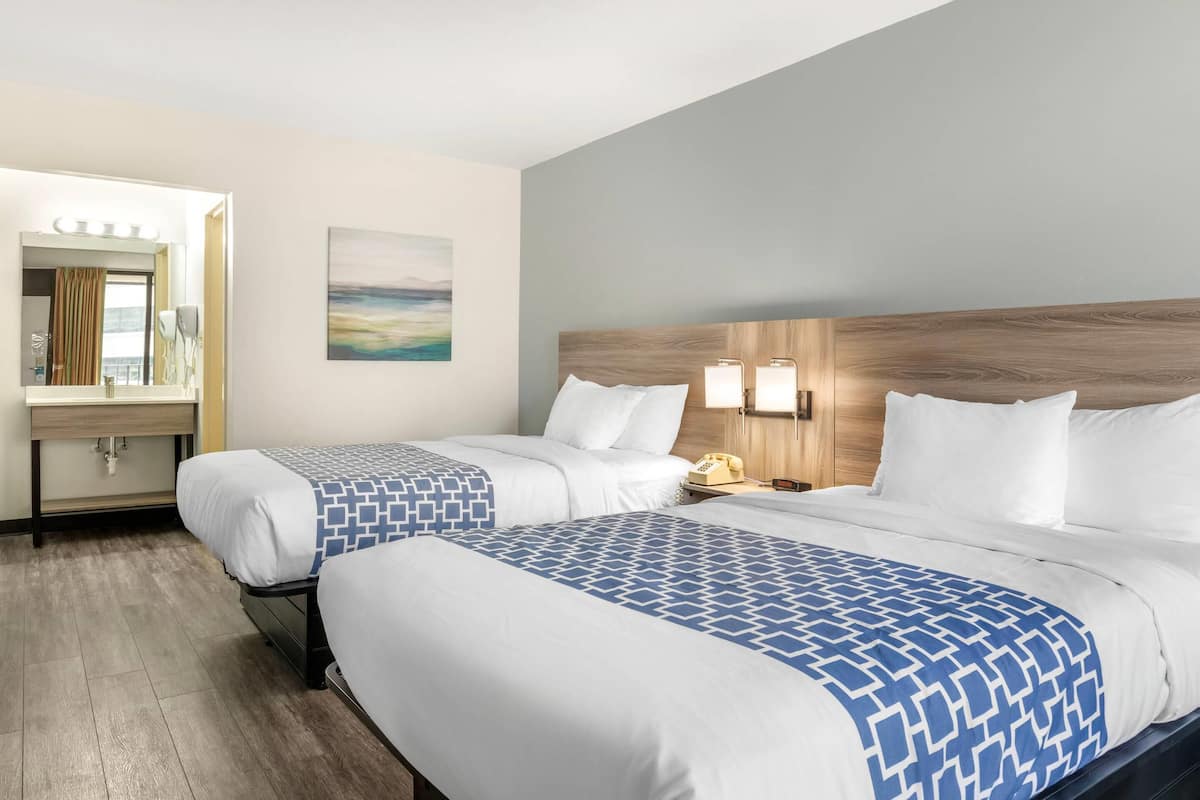 A hotel room with two beds, a bathroom, and a view of the sea.
