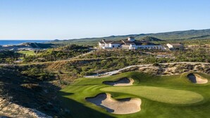 A golf course with bunkers and a clubhouse in the background.